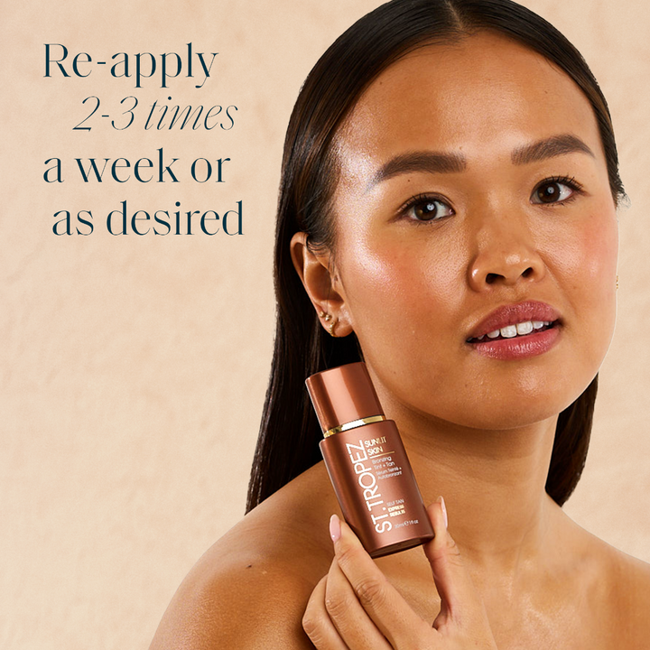 Woman holding St Tropez bronzing tint bottle with glowing skin and reapply instructions on beige background