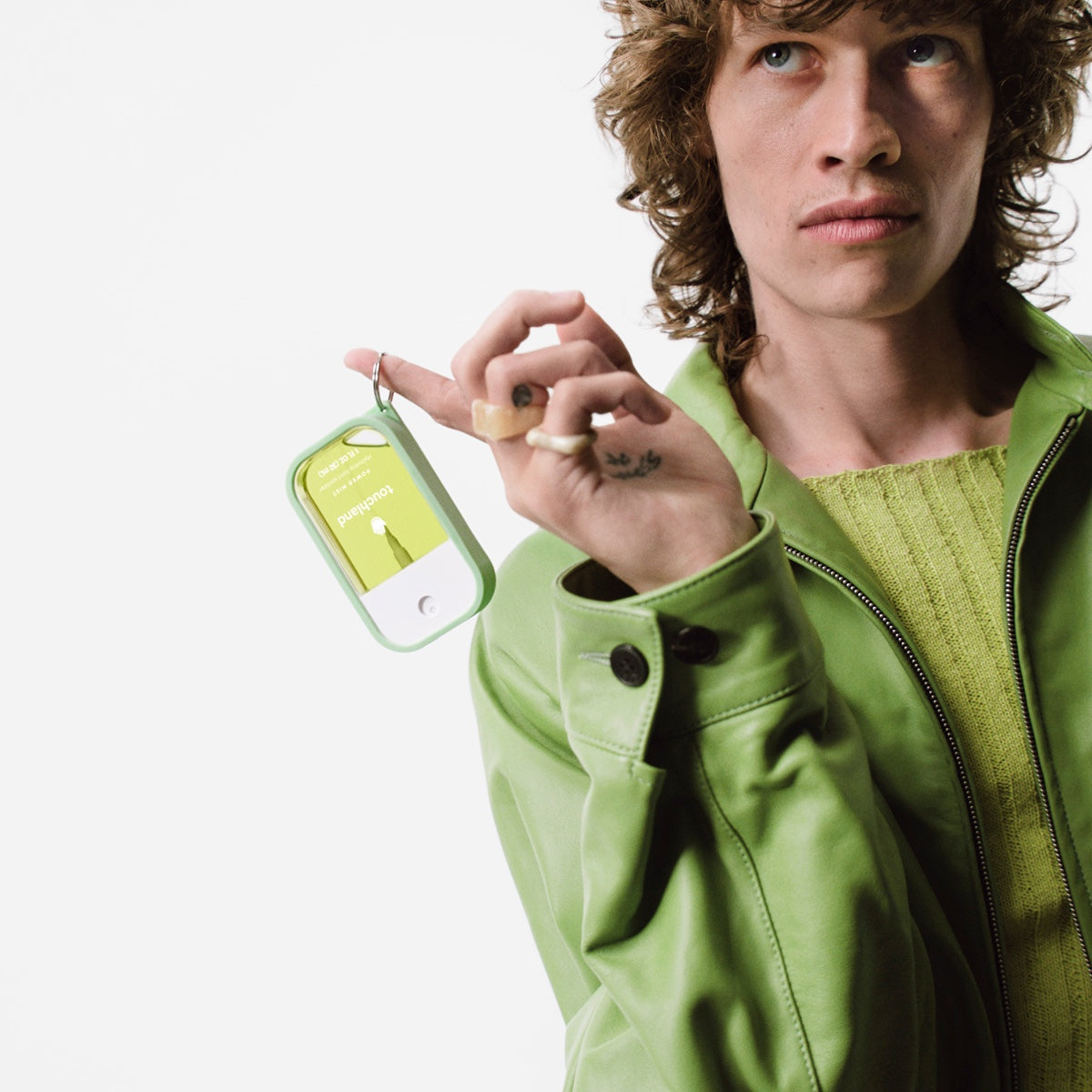 Model holding Touchland hand sanitizer mist in a vibrant green packaging for on-the-go use