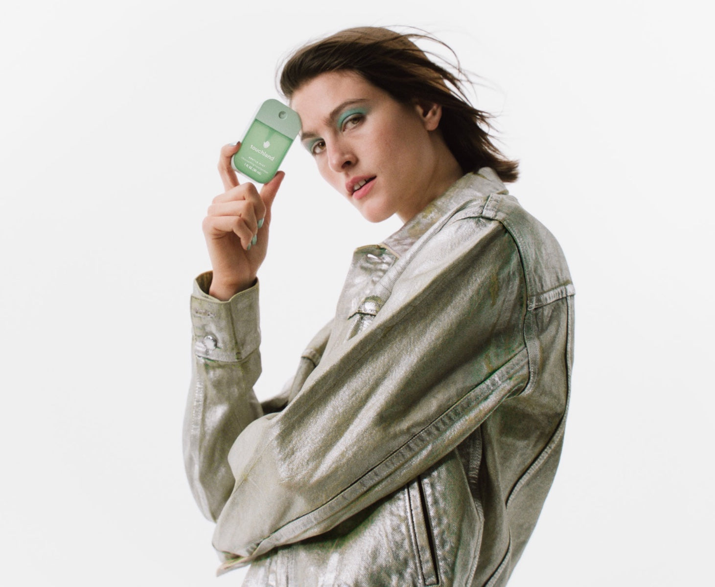 Model holding Touchland lily of the valley hand sanitizer in a stylish metallic jacket
