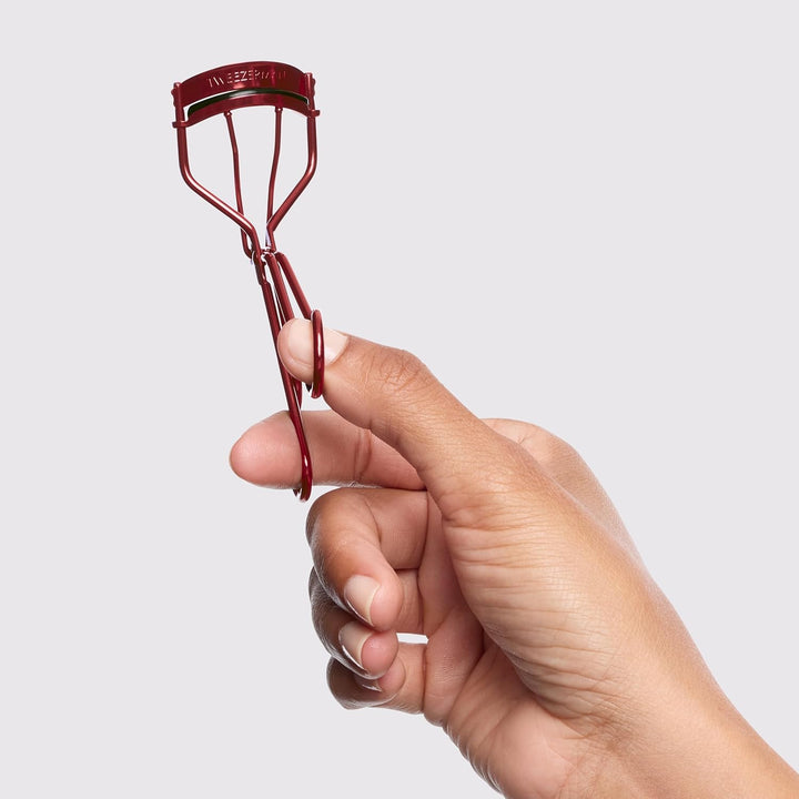 Tweezerman lash curler set held in a hand for precise eyelash curling