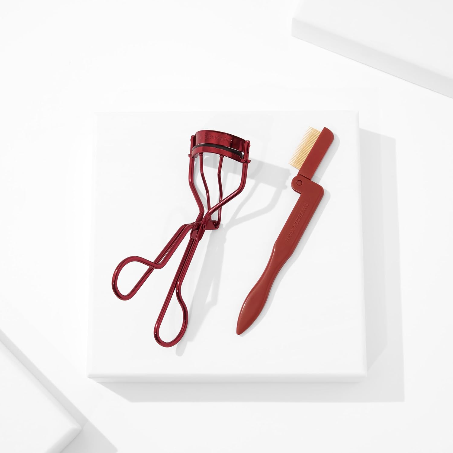 Tweezerman lash curler set featuring a red eyelash curler and lash comb for perfect curls
