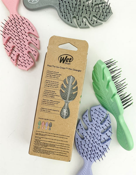 Wet Brush eco-friendly mini hairbrushes in pink, gray, green, and purple with leaf design on white background