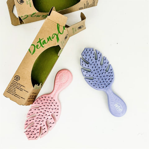 Wet Brush eco-friendly mini hairbrushes in pink and purple with leaf-shaped bristles and recyclable packaging