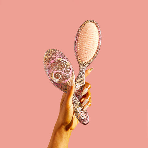Wet Brush Wicked detangling brush with decorative swirl design held against pink background