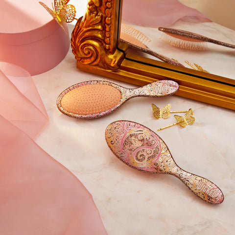 Wet Brush Wicked detangling brush with ornate pink and gold paisley design on marble surface