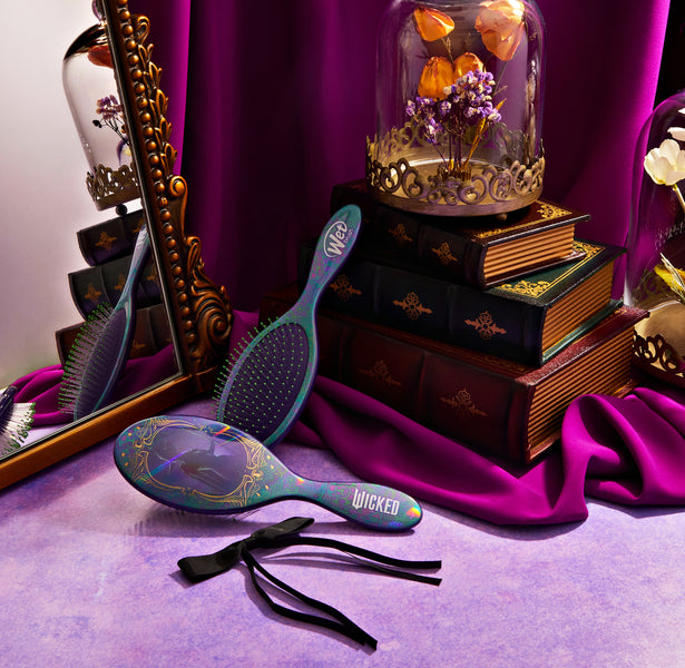 Wet Brush Wicked detangling brush with floral design placed near mirror and vintage books