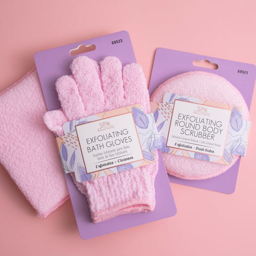 Cala exfoliating bath gloves in pink with packaging on a pink background alongside matching exfoliating round body scrubber