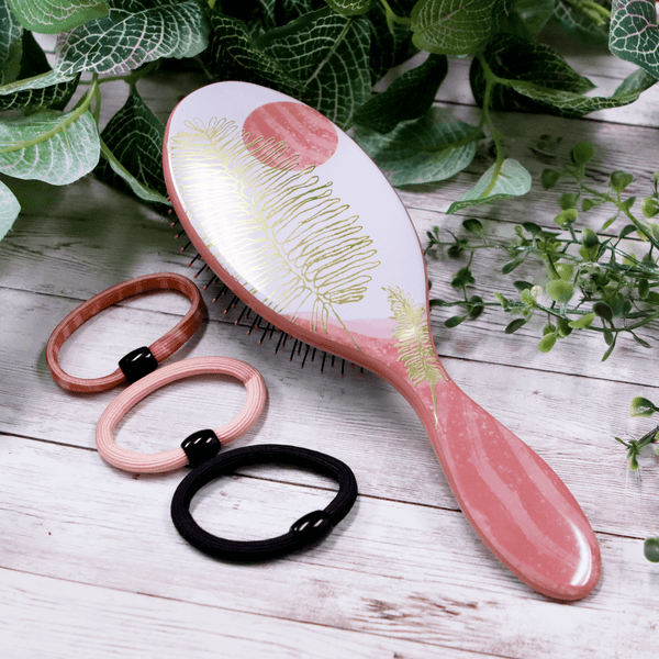 Wet Brush hair styling kit with pink and gold brush and three matching hair ties on wooden surface