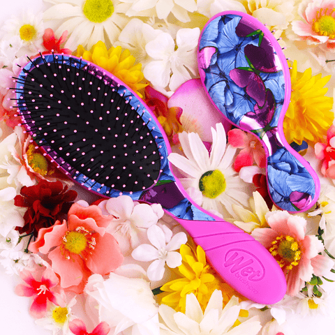 Wet Brush Pro Detangler Metamorphosis with pink handle and blue floral design resting on colorful flowers